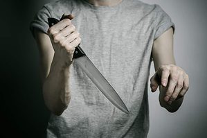 Murder and Halloween theme: a man holding a knife on a gray background studio